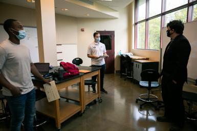 Dr. Cale Stolle presents scholarships to senior engineering students Ryan Lasauskas, 左, 肯尼·肯普, 正确的. They are standing in a classroom in the Lied Science and Mathematicsbuilding. 